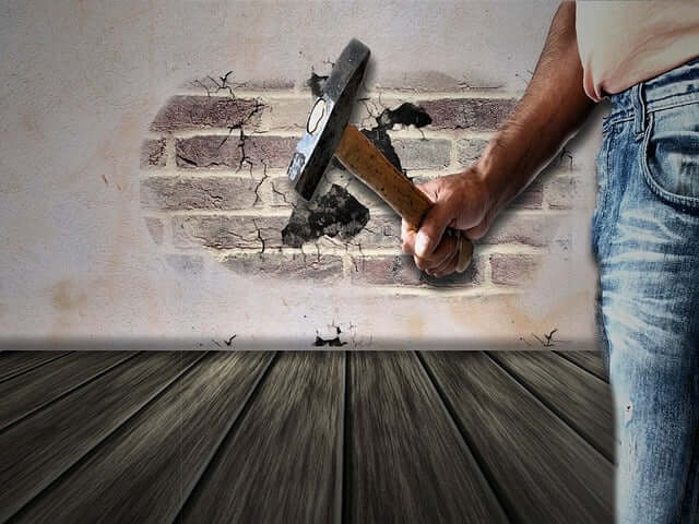 Man demolishing a wall with a hammer