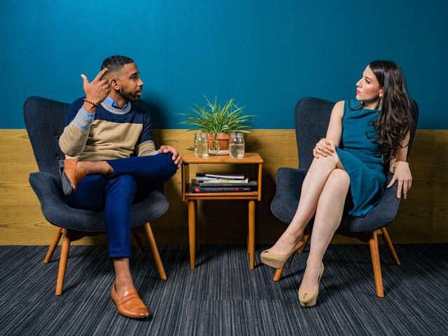 A man and a woman having a conversation while sitting on confortable chairs