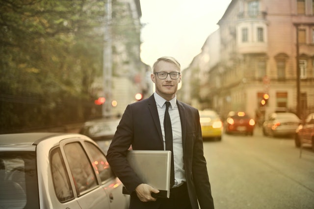 smiling businessman with laptop on street