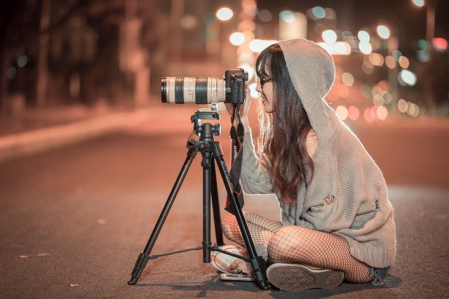 Woman using camera and tripod in the road