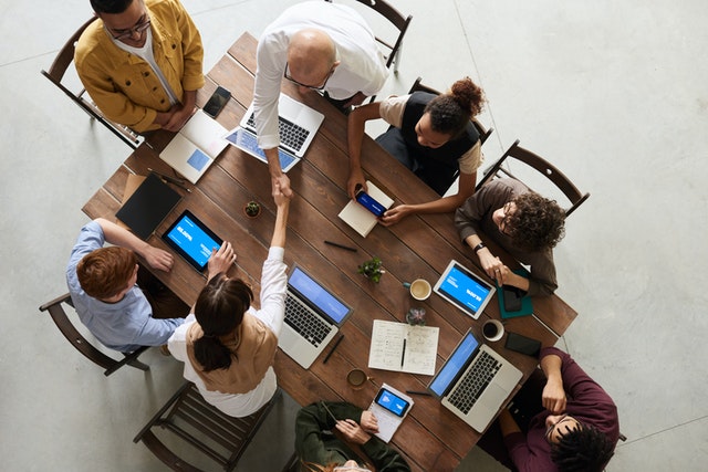 view from the top of people sitting around the table with laptops opened