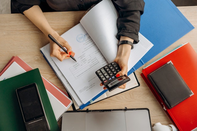Woman holding a calculator and writing financial reports