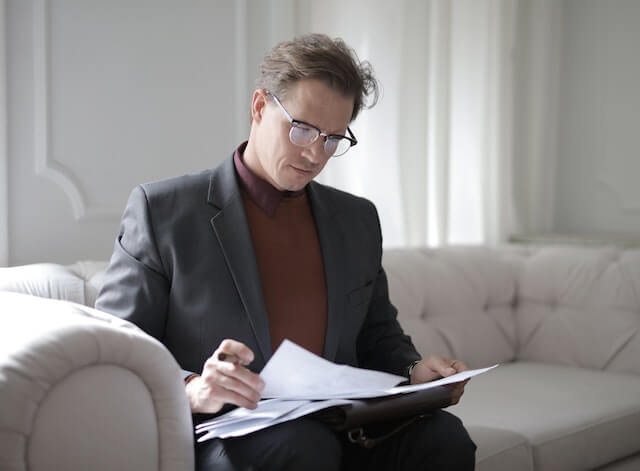 Elegant man sitting on a couch, reading some papers.